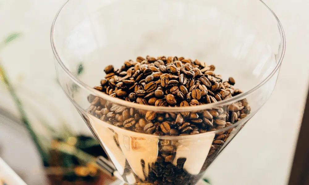 Kaffeebohnen in Kaffeemühle mit goldenem Rand und Belichtet