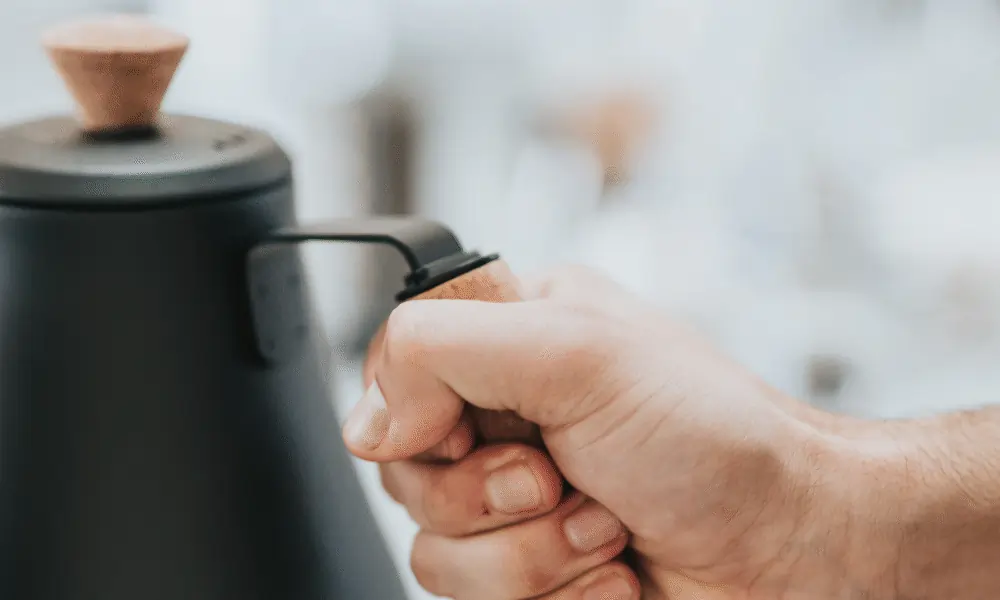 Schwarzer Wasserkocher und Hand von Mann