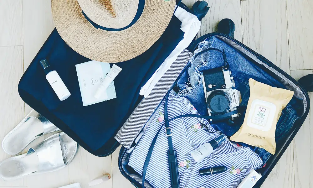 Hardcase Reisekoffer in schwarz mit Kleidung und Kamera und Sonnenhut